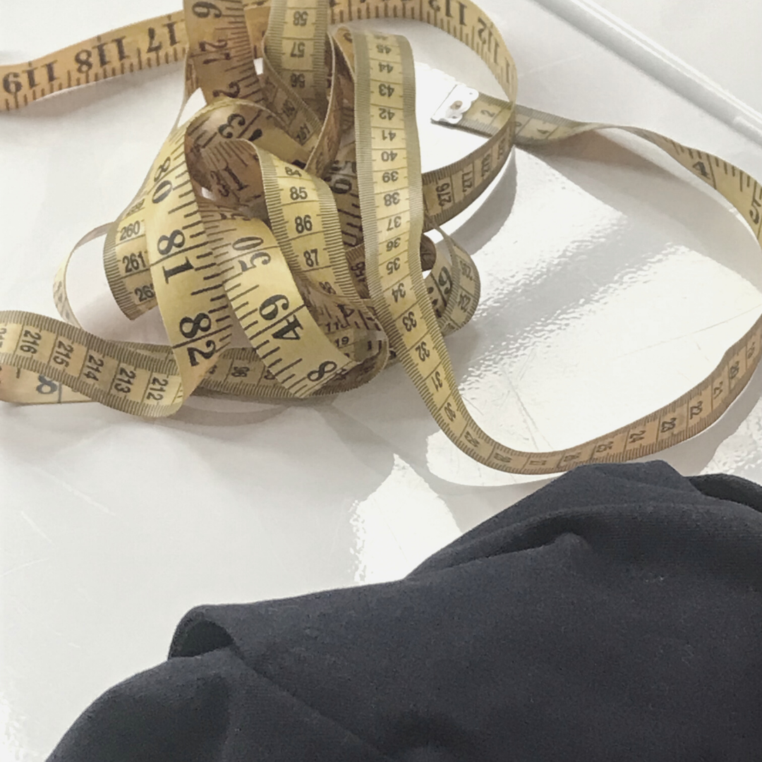 Close up of measuring tape and fabric on white table