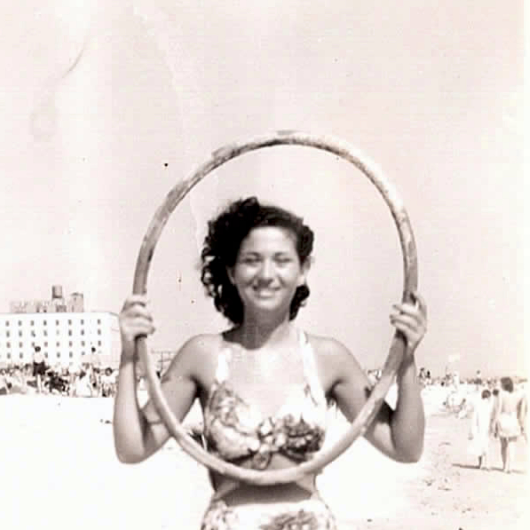 Woman on a beach holding a hula hoop