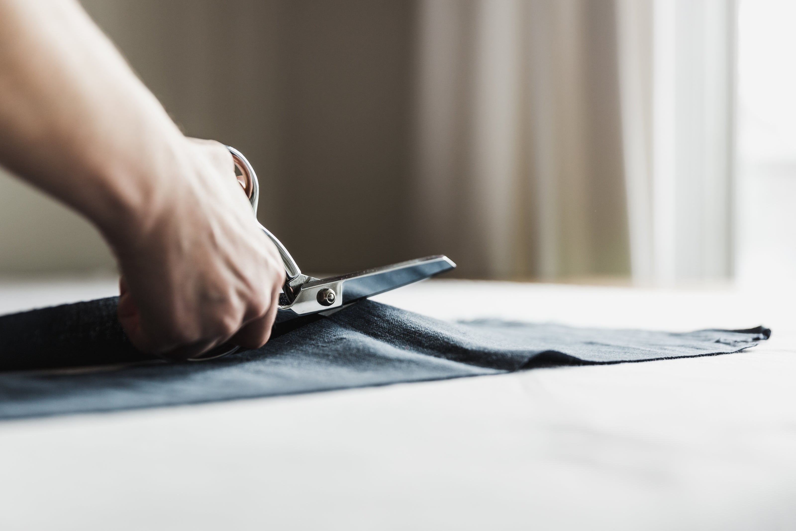 Close up of person cutting fabric with scissors