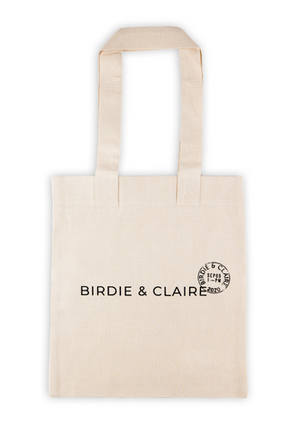 Image of cotton tote bag in neutral color with Birdie & Claire logo printed in black. Bag is on a white background.